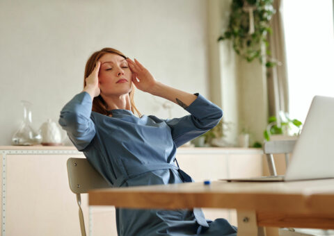 a woman at a desk suffering from a headache