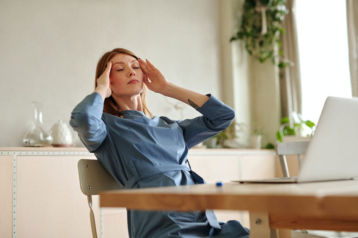 a woman at a desk suffering from a headache